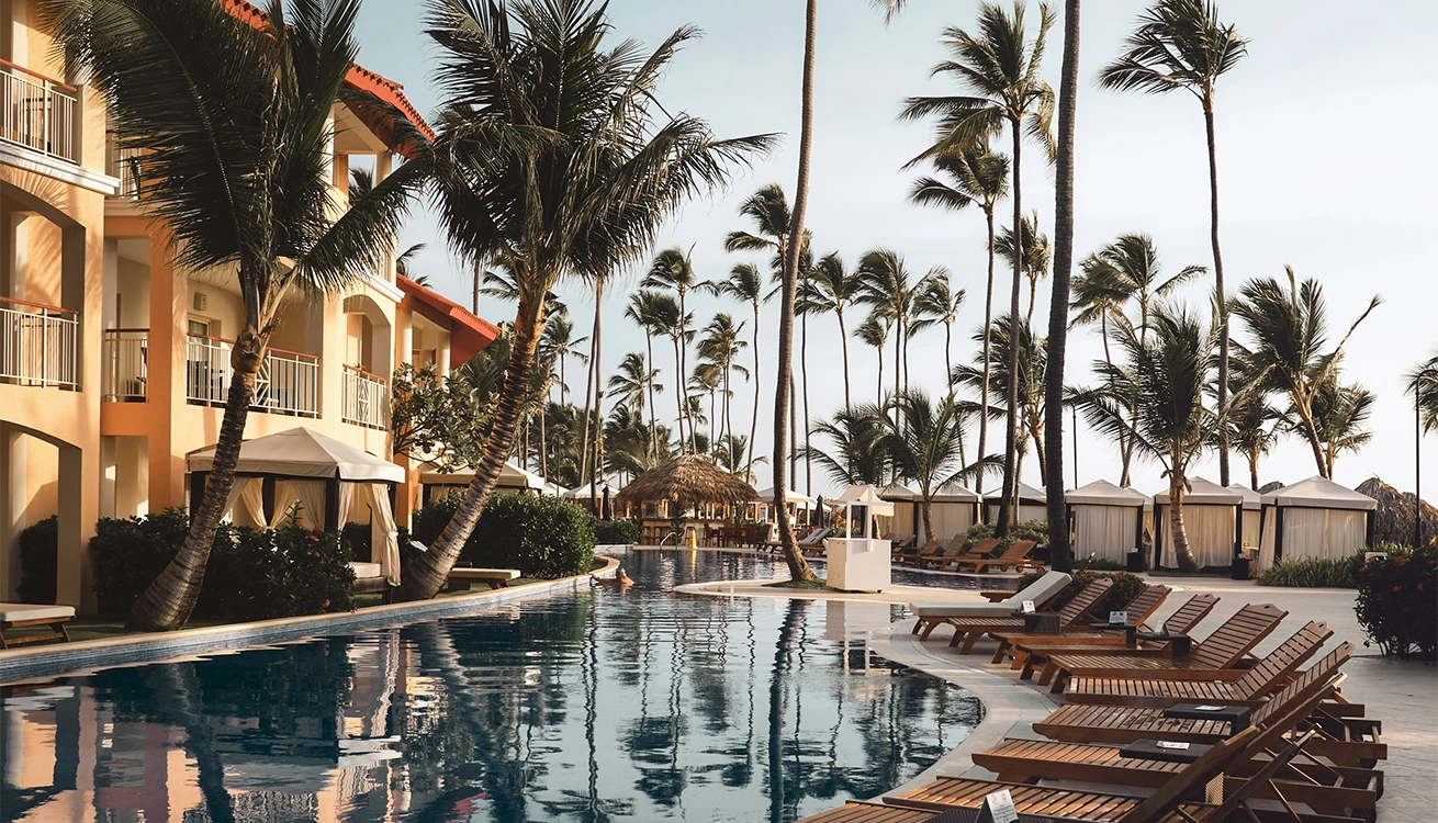 Swimming pool with palm trees and poolside loungers